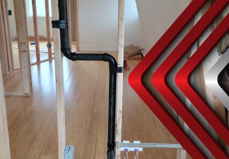 Black ABS drain pipe and copper water lines installed in an unfinished home during new construction plumbing rough-in